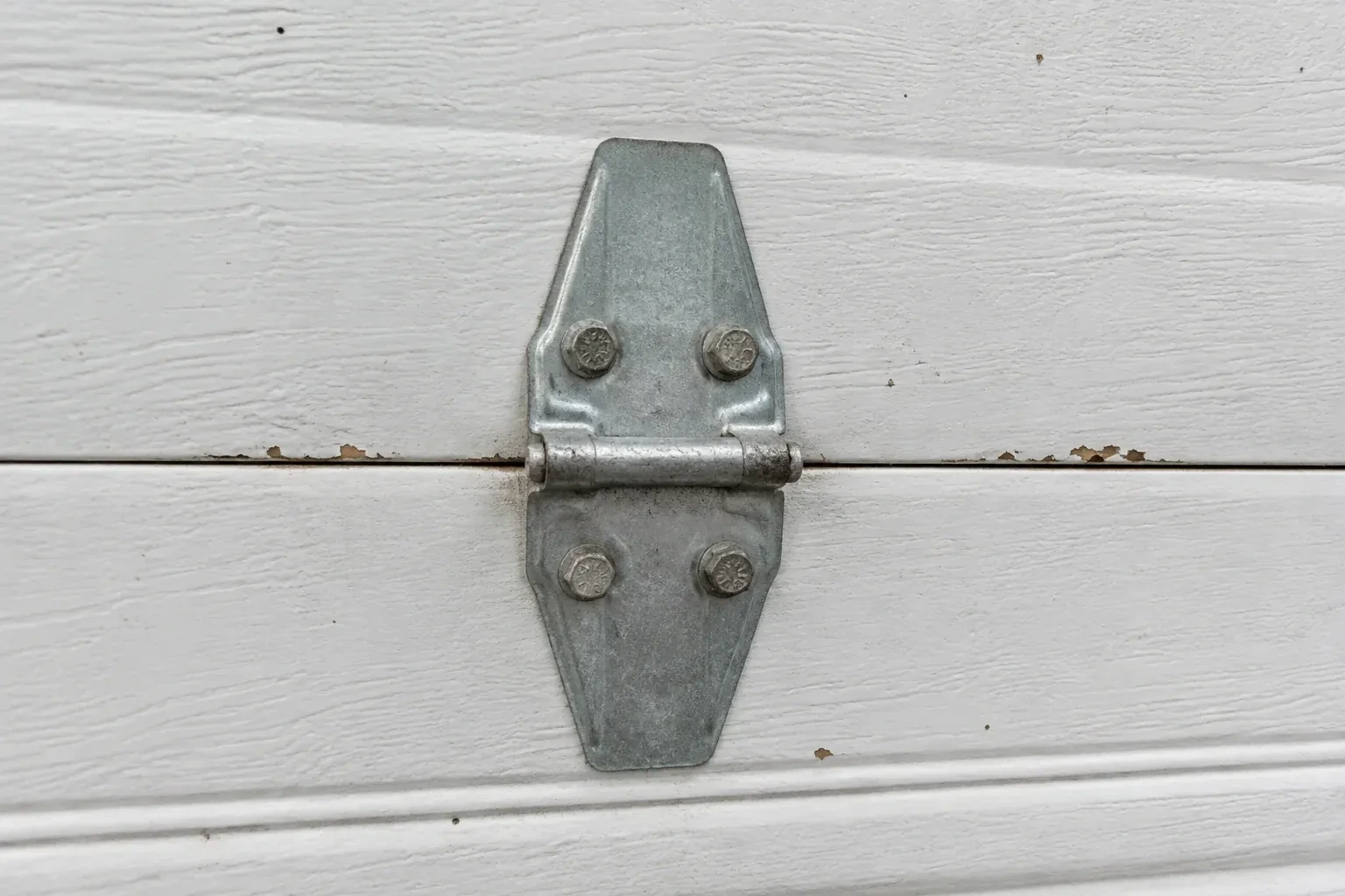 Metal center hinge across a seam in a white sectional garage door. — Garage Door Hinge Replacement, Toronto